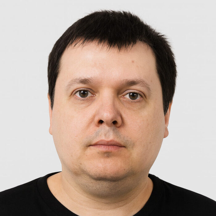 Портрет на мъж с черна тениска и спокойен израз на лицето.