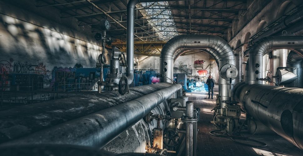 Изоставено индустриално пространство с графити и индустриални елементи, предаващо атмосфера на забвение.