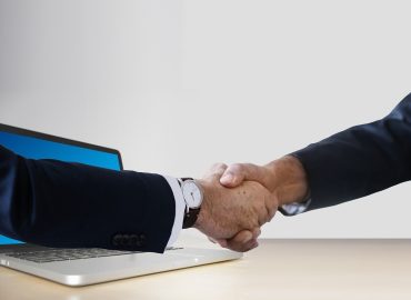 Цифрова ръка за ръка, символизираща виртуална свързаност в бизнес среда.