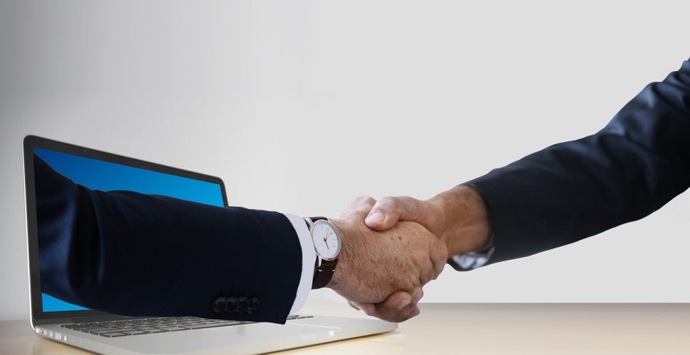 Цифрова ръка за ръка, символизираща виртуална свързаност в бизнес среда.