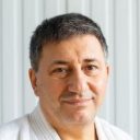 Усмихнат инструктор по бойни изкуства в бял гӣ Инструктор по бойни изкуства с усмивка в бял гӣ на модерен фон.