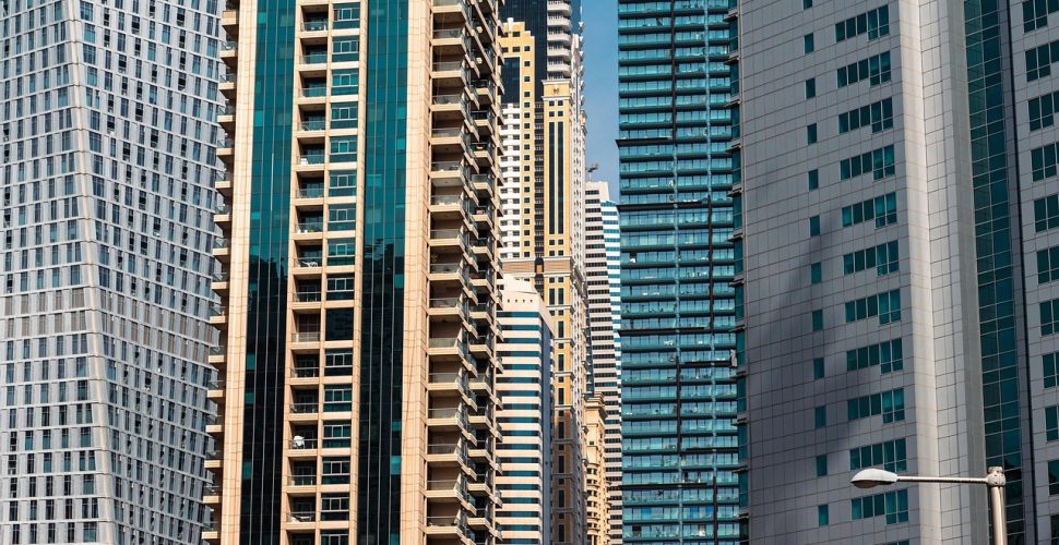 Модерни небостъргачи в градски пейзаж с разнообразни архитектурни стилове и динамика.