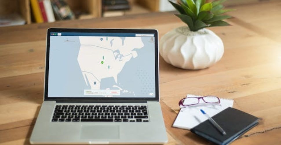 Съвременен офис с лаптоп, растения и рафт с книги на дървена маса.